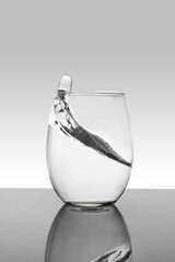 Crystal glass with moving water and white background with gray gradient