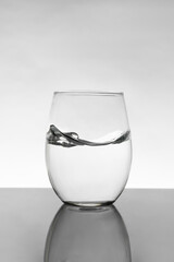 Crystal glass with moving water and white background with gray gradient