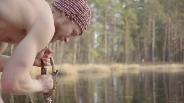 SLOW MOTION - topless ice bather smashing the ice with a stick to make a hole