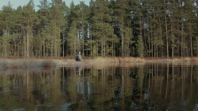 TRACKING ESTABLISHING shot of a meditating ice bather by a frozen lake