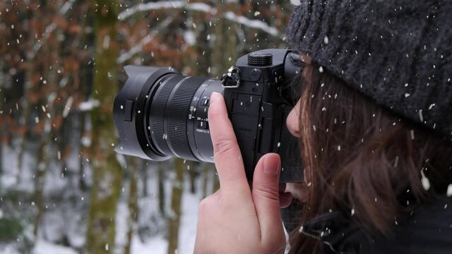 Woman taking photos of winter forest during heavy snowfall, close up view