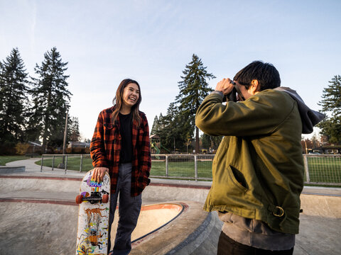Young Indigenous male photographer and non-binary skater outdoors