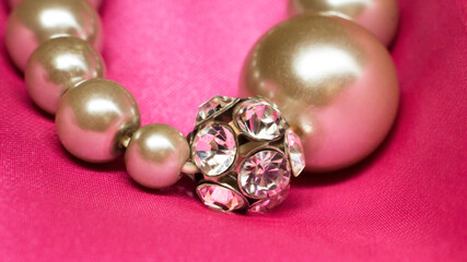 Bracelet made of beads and rhinestones on a pink background