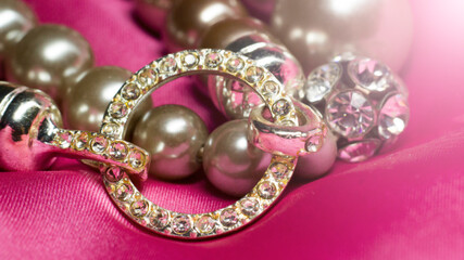 Bracelet made of beads and rhinestones on a pink background