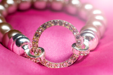 Bracelet made of beads and rhinestones on a pink background