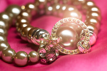Bracelet made of beads and rhinestones on a pink background