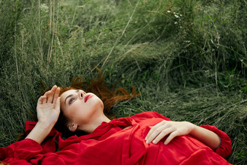 pretty woman in red dress lies on the grass freedom landscape