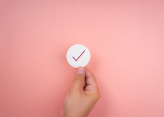 Checklist concept, minimal style. Check mark icon symbols on white round sponge in hand on pink...