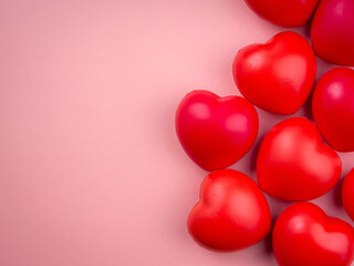Group of red heart ball on pink pastel background with copy space. Concept of love, care, sharing, giving, well-being, and donation concepts, minimal style.
