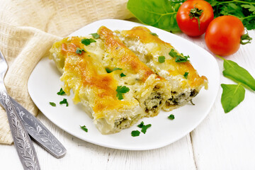 Cannelloni with curd and spinach in plate on light board