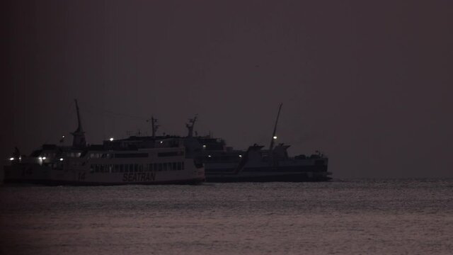 Silhouette of two ferry boats travelling through the frame in the dusk sunlight - Koh Samui in Thailand