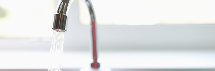 Pure water flows from faucet in kitchen closeup