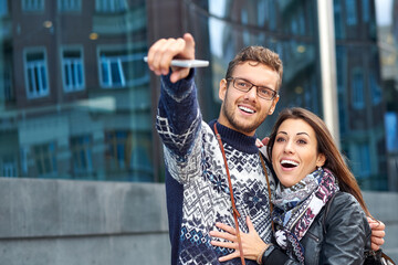 Happy love couple of tourists taking pointing to a landmark or showplace in the city