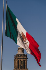 Bandera de México ondeando frente a cúpula de catedral metropolitana