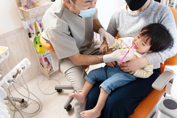 歯医者で歯磨きの指導をうける赤ちゃんとお母さん