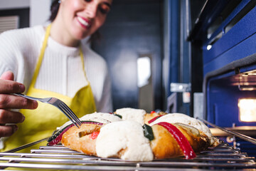 mexican woman baking a traditional rosca de reyes or epiphany cake on the oven in kitchen at home for Kings Day in Mexico Latin America	