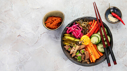Bibimbap with snacks on gray background.