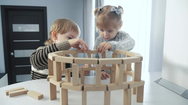 play in designer wooden sticks teamwork. happy family kids little boy a and girl play lifestyle in wooden blocks cubes build house. children brother and sister collect designer development of fine