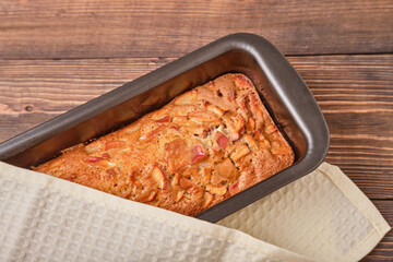 Apple pie in a baking tray on a brown wooden table. Apple charlotte. Homemade apple pie. Close-up, top view