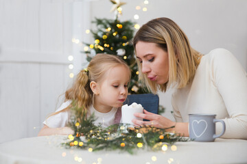 mother and child daughter drink hot cocoa with marshmellow on Christmas holidays at home. family...