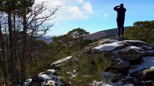 Man contemplating the snowy landscape of the mountains on a rock. Guadarrama Madrid.