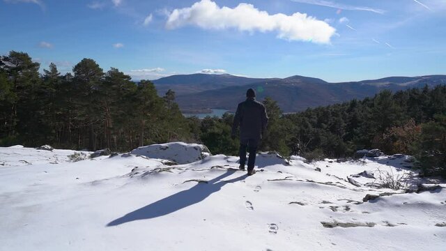 Man walking on the snow on the snowy mountain and looking out into the green valley. Guadarrama Madrid.