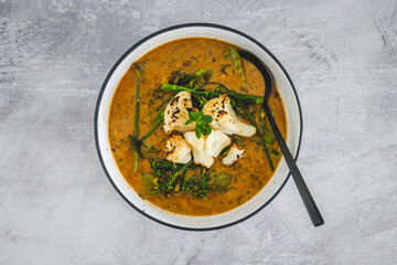vegan yellow cauliflower curry with carrots celeri and parsley, healthy plant-based food