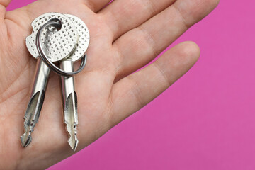 Image of metal keys in the palm of a man on a colored background.