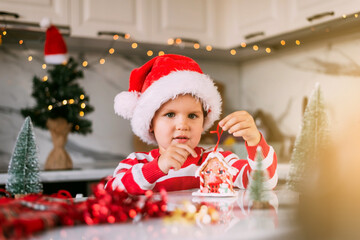 Christmas picture with a toy house and a child in a Santa hat.