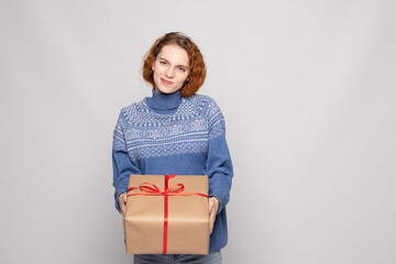 young girl in a sweater is holding a gift on a white background