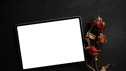 Tablet touchscreen mockup with dry roses on black background.