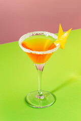 Sidecar classic alcoholic cocktail with cognac, liqueur, lemon juice and ice. Pink and green pop background, copy space