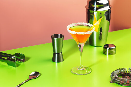 Sidecar classic alcoholic cocktail with cognac, liqueur, lemon juice and ice. Pink and green pop background, copy space