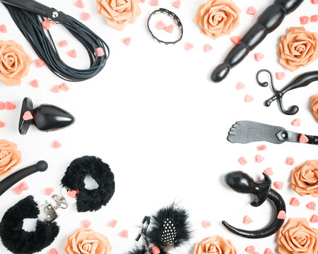 The frame is made of various sex toys, roses and hearts. Dildo, vibrator, butt plug, spanking pad, leather whip and other sex toys are on a white background. Valentine's day sex shop template.