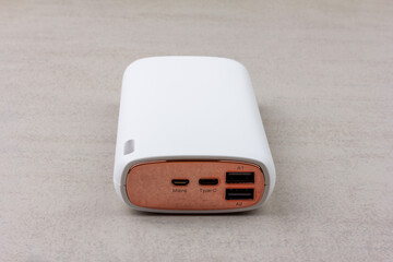 white power bank for charging smartphones and various digital devices on a gray background close-up