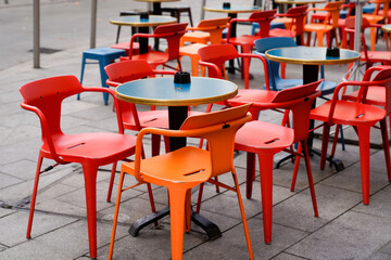 Fototapeta na wymiar Charming red and orange chairs on cafe outdoor restaurant cafe and steel tables colorful terrace