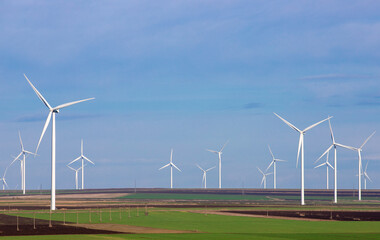 Eolian farm renewable energy on a field against blue sky