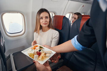 Airline hostess passing meal to female passenger