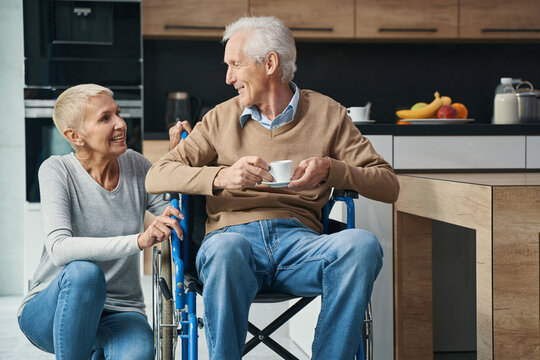Pleased aged woman talking with her disabled man