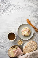 Modern  healthy breakfast. Crispy buckwheat and rice cake with hummus, ham and cheese and hot drink on white table at the morning.