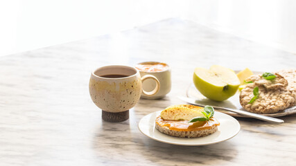 Obraz na płótnie Canvas Healthy breakfast. Crunchy buckwheat and rice snack with almond butter and apple, hot drink on the table. Large image for banner.
