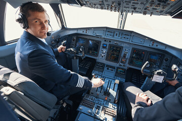 Pleased aircraft captain smiling while pulling thrust lever