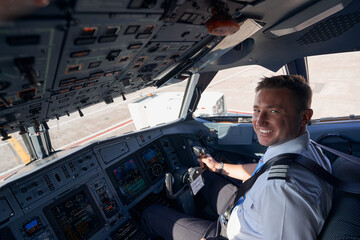 Happy airplane pilot smiling to camera with hand on wheel
