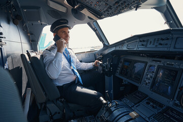 Plane captain talking on the phone in cockpit © Viacheslav Yakobchuk