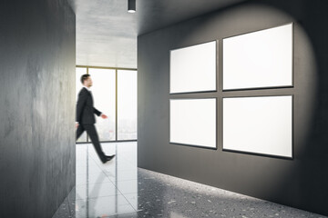 Businessman walking in modern gallery interior with mock up poster on walls and window with city view. Museum or apartment concept.
