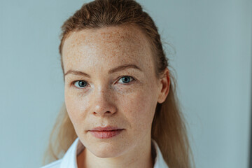 Beautiful woman with read hair and freckles. Close up portrait against black background