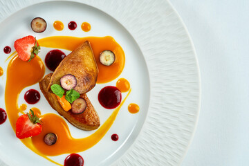 Fried foie gras with berry sauce in a white plate on a white plate