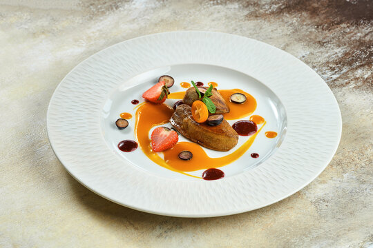 Fried foie gras with berry sauce in a white plate on a white plate