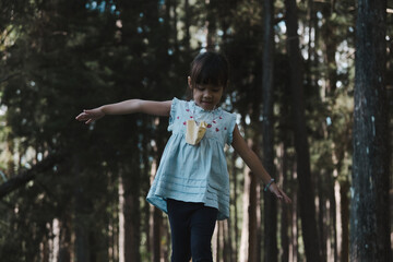 Cute little girl walking on a log in the park. child on the balance beam. Play is learning in...