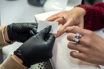 gorgeous manicure master in special black gloves works on the girl's nails.